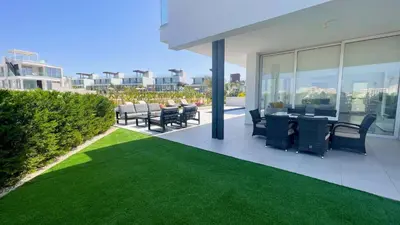 a patio with chairs and a table and grass at Olivine Waves in Protaras