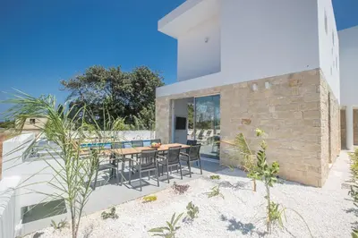 a house on the beach with a table and chairs at Vie Bleu Villas in Protaras