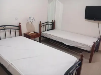 two twin beds in a room with a tv at BarLee's Apartment in Paralimni