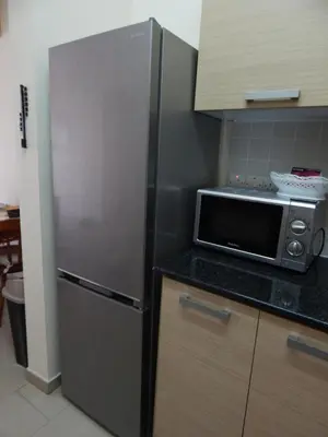 a stainless steel refrigerator in a kitchen with a microwave at BarLee's Apartment in Paralimni