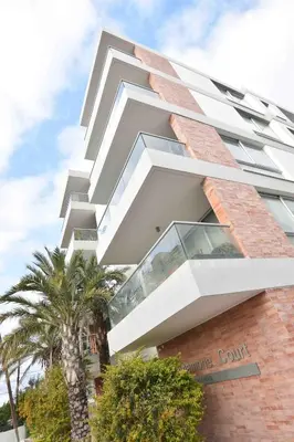 a large white building with palm trees in front of it at Glabur Stays - The Amazing 1 BDR - Executive apt Nicosia Center Free Parking & WiFi in Nicosia