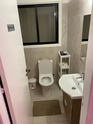 a bathroom with a toilet and a sink and a window at City Comfort Rooms in Larnaka