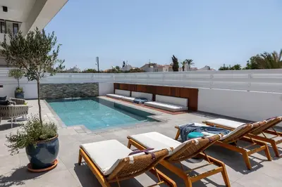 a patio with chairs and a swimming pool on a building at Chris Le Mare Gold Luxury Villa in Protaras