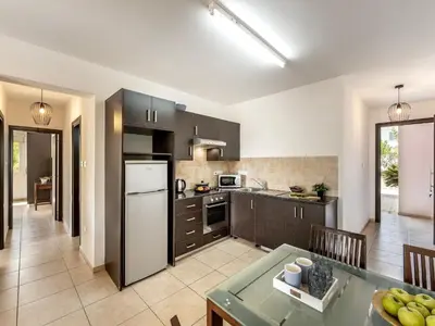 a kitchen with a refrigerator and a table with a table sidx sidx at Mythical Sands Resort in Protaras