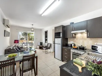 a kitchen and living room with a table and chairs at Mythical Sands Resort in Protaras