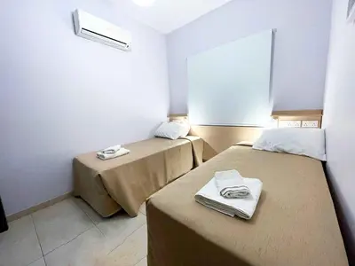 a small room with two beds and a window at Topikos Apartments in Ayia Napa