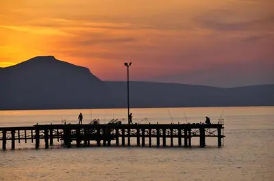 a pier with people fishing on the water at sunset at Apt Misia Enas - Modern 2 Bedroom Apartment With Sea Views - Close To Ayia Napa in Ayia Napa