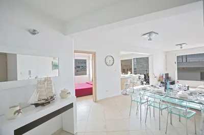 a white dining room with a table and chairs at Apt Lasonos Asimi - Luxury 3 Bedroom Protaras Apartment - Communal Pool in Protaras