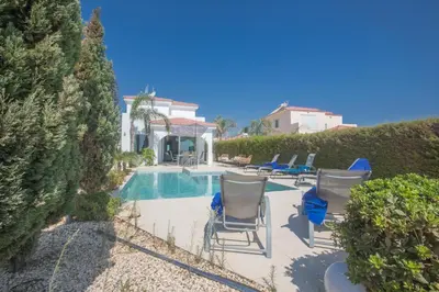 a swimming pool with chairs and a house at Sunrise Villa 12 in Ayia Napa