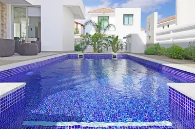 a swimming pool in front of a house with blue tiles at Villa Luna in Protaras