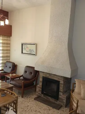a living room with a fireplace and two chairs at Kakopetria Heights in Kakopetria