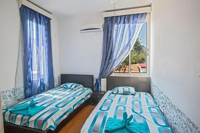 two beds in a room with a window at Villa Mavris - Lovely 4 Bedroom Villa With Private Pool In Central Ayia Napa in Ayia Napa