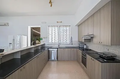 a large kitchen with wooden cabinets and black counter tops at Villa Mavris - Lovely 4 Bedroom Villa With Private Pool In Central Ayia Napa in Ayia Napa
