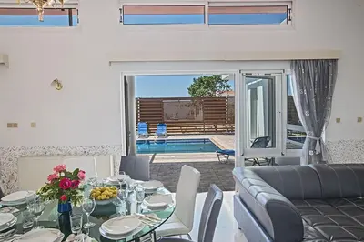 a living room with a table and a couch and a pool at Villa Mavris - Lovely 4 Bedroom Villa With Private Pool In Central Ayia Napa in Ayia Napa