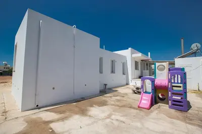 a white building with a playground equipment next to it at Villa Mavris - Lovely 4 Bedroom Villa With Private Pool In Central Ayia Napa in Ayia Napa