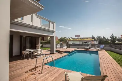 a swimming pool with chairs and a table and a house at Villa Petreris Dyo - Lovely 3 Bedroom Central Ayia Napa Villa With Pool in Ayia Napa