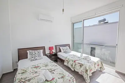 a bedroom with two beds and a large window at Villa Ochosto Eos - Luxury 5 Bedroom Protaras Villa With Private Pool - Close in Protaras