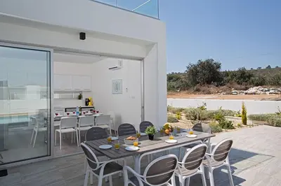 a dining area with a table and chairs and a kitchen at Villa Ochosto Eos - Luxury 5 Bedroom Protaras Villa With Private Pool - Close in Protaras