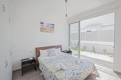 a bedroom with a bed and a large window at Villa Ochosto Eos - Luxury 5 Bedroom Protaras Villa With Private Pool - Close in Protaras
