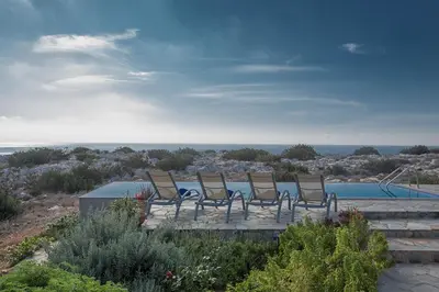 a group of chairs sitting next to a pool at Villa Ayia Napa Foothills, Exquisite 5Bdr Ayia Napa Villa With Pool in Ayia Napa