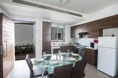 a kitchen with a table with chairs and a white refrigerator at Villa Petreris Enas - Stunning 3 Bedroom Central Ayia Napa Villa With Pool in Ayia Napa