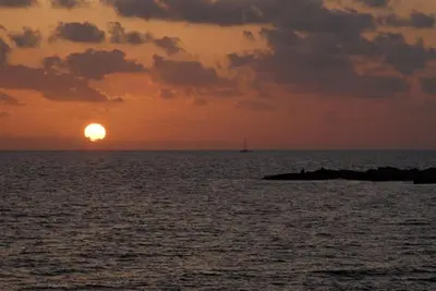 a sunset over the ocean with a boat in the distance at Villa Petreris Enas - Stunning 3 Bedroom Central Ayia Napa Villa With Pool in Ayia Napa