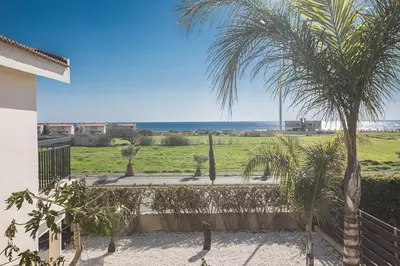 a view of a yard with palm trees and the ocean at Villa Magusta - Modern 4 Bedroom Ayia Thekla Villa With Pool in Ayia Napa