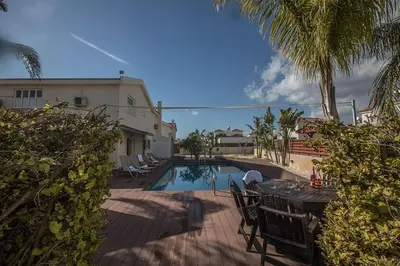 a swimming pool with a table and chairs next to a house at Villa Magusta - Modern 4 Bedroom Ayia Thekla Villa With Pool in Ayia Napa