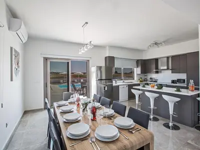 a kitchen and dining room with a wooden table and chairs at Villa Ioanni Chrysos - Luxury And New 6 Bedroom Protaras Villa in Protaras
