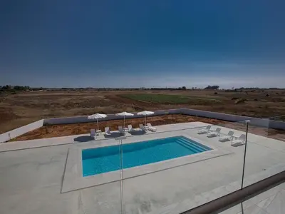 a swimming pool with chairs and umbrellas at Villa Ioanni Chrysos - Luxury And New 6 Bedroom Protaras Villa in Protaras