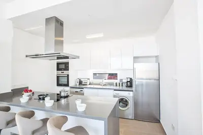 a kitchen with white walls and a stainless steel refrigerator at Villa Olive Titan, Brand New,Exquisite 5Bdr Protaras Villa With Pool in Protaras
