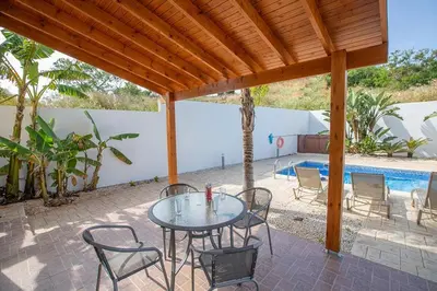 a patio with a table and chairs and a pool at Villa Kanthos - Beautiful 4 Bedroom Protaras Villa With Pool in Protaras
