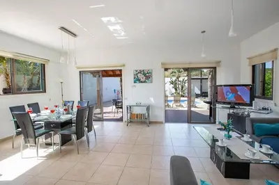 a living room with a table and chairs and a television at Villa Kanthos - Beautiful 4 Bedroom Protaras Villa With Pool in Protaras
