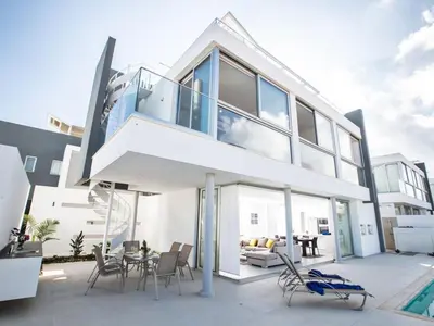 a large white house with glass doors and a patio at Villa Panemorfi - Luxury Brand New 3 Bedroom Protaras Villa With Private Pool in Protaras