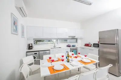 a white kitchen with a table and white chairs at Villa Ochosto Selene - Stunning 5 Bedroom Protaras Villa With Private Pool in Protaras