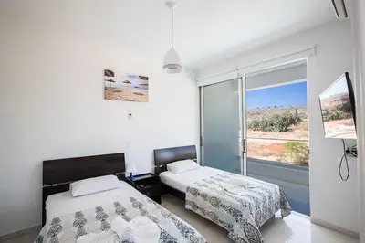 a bedroom with two beds and a large window at Villa Ochosto Selene - Stunning 5 Bedroom Protaras Villa With Private Pool in Protaras