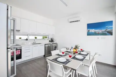 a white kitchen with a table and white chairs at Villa Ochosto Loux - Fabulous 5 Bedroom Protaras Villa With Private Pool in Protaras