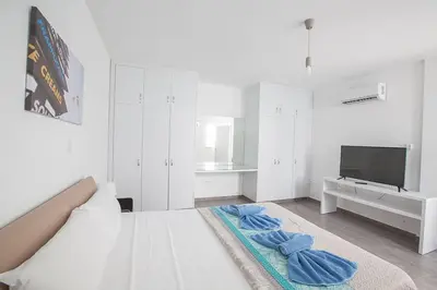 a white bedroom with a bed and a flat screen tv at Villa Ochosto Loux - Fabulous 5 Bedroom Protaras Villa With Private Pool in Protaras