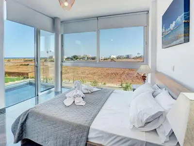a bedroom with a large bed with a large window at Villa Manta Chrysos - Brand New Luxury 3 Bedroom Protaras Villa in Protaras