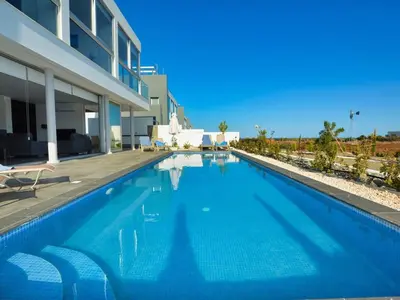 a large blue swimming pool in front of a building at Villa Manta Chrysos - Brand New Luxury 3 Bedroom Protaras Villa in Protaras