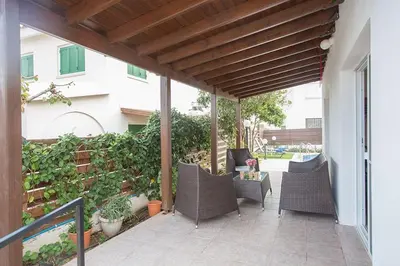 an outdoor patio with wicker chairs and a wooden pergola at Villa Kavo Sunshine - Beautiful 3 Bedroom Protaras Villa With Private Pool in Protaras