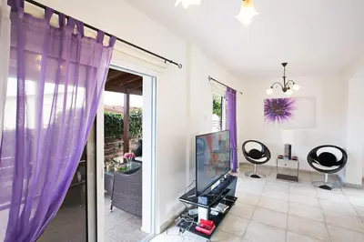 a living room with a tv and purple curtains at Villa Kavo Sunshine - Beautiful 3 Bedroom Protaras Villa With Private Pool in Protaras