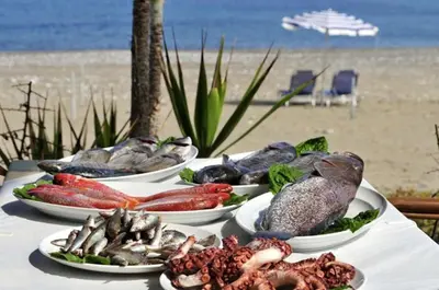a table with four plates of seafood on the beach at Central Protaras Villa 3 Bedrooms Private Pool Villa Dafnis Morfi in Protaras