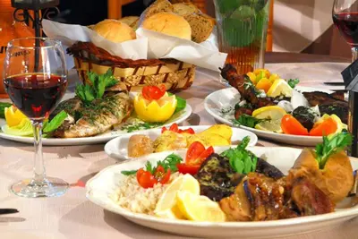 a table with plates of food and a glass of wine at Central Protaras Villa 3 Bedrooms Private Pool Villa Dafnis Morfi in Protaras