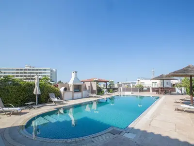 a large swimming pool with chairs and umbrellas at Villa Lefko Sunshine - Lovely 4 Bedroom Protaras Villa With Pool in Protaras