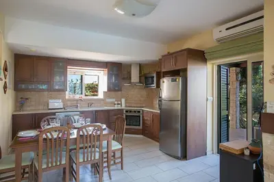 a kitchen with a table and a stainless steel refrigerator at Villa Matronas Titan - Stunning 5 Bedroom Protaras Villa With Private Pool in Paralimni