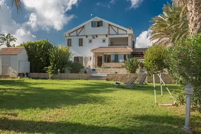 a large white house with a yard with a house at Villa Matronas Titan - Stunning 5 Bedroom Protaras Villa With Private Pool in Paralimni