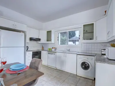 a kitchen with white appliances and a wooden table at Villa Oforo Selene - Stunning 4 Bedroom Villa - By Fig Tree Bay Beach - Sea View in Protaras