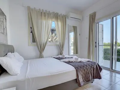 a white bedroom with a bed and a window at Villa Oforo Selene - Stunning 4 Bedroom Villa - By Fig Tree Bay Beach - Sea View in Protaras