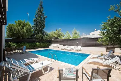 a swimming pool with chairs and a table and a swimming pool at Villa Protaras Eos, Modern 3Bdr Protaras Villa With Pool, Short Walk in Protaras